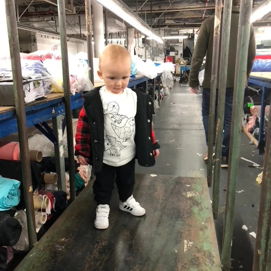 Young child visiting a busy New York garment factory floor