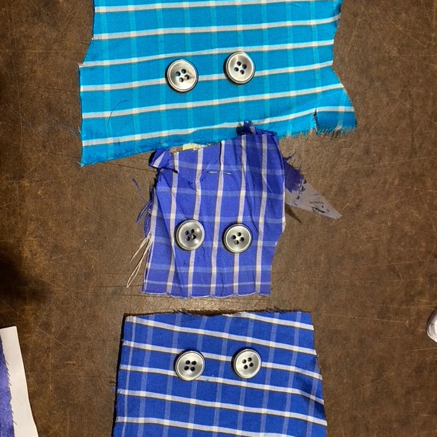 Blue plaid fabric samples with buttons arranged on a worktable