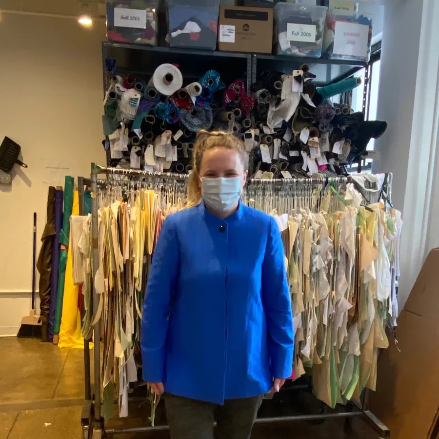 Monika in a garment showroom surrounded by clothing racks